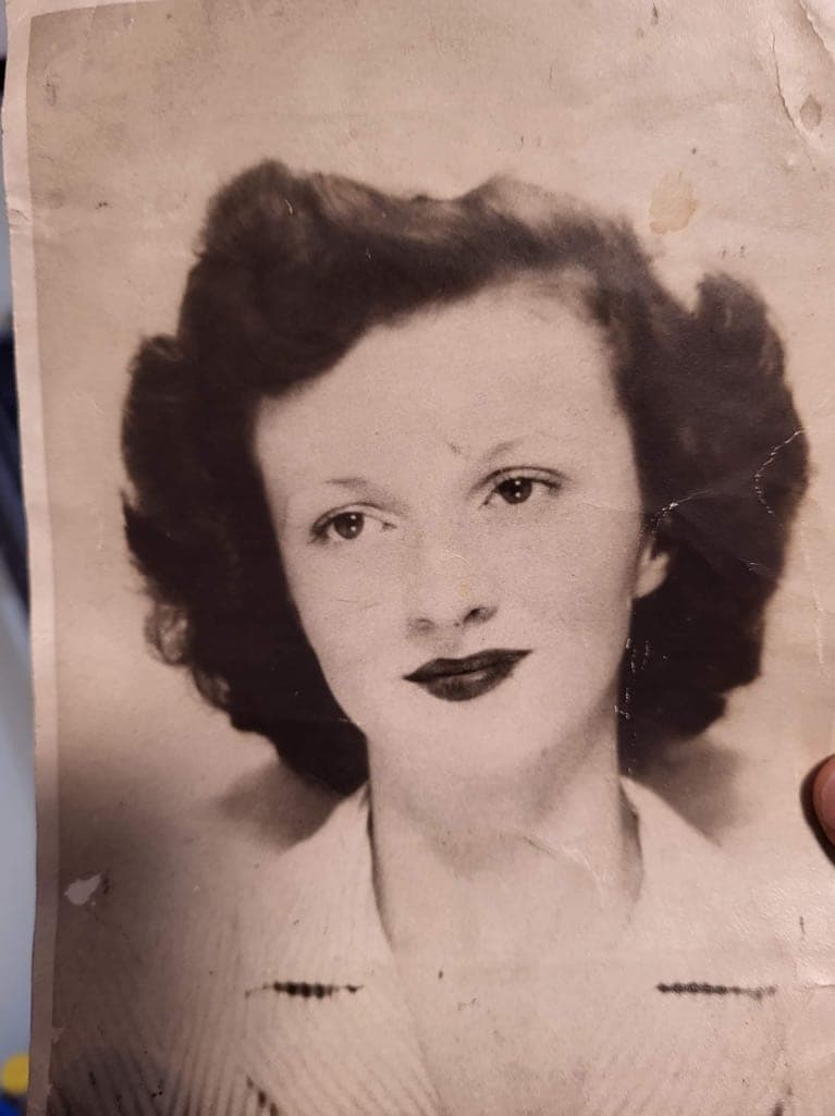 A young woman in a pale sweater, photographed in the 1940s. The print is creased, marked and browning at the edges.